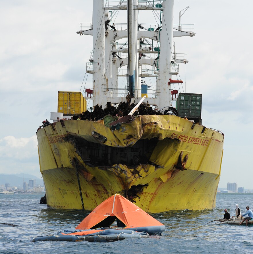 A life raft from the sunken ferry MV Thomas Aquinas floats in front of the cargo ship it collided with on Friday.