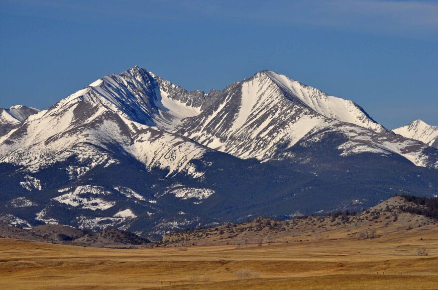 Snow-covered mountain peaks surrounded by dark yellow land