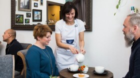 2 guests watch as a staff member pours them tea