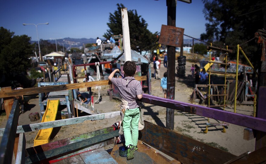 A boy paints the railings of a wooden fort at the Berkeley Adventure Playground. Nails, hammers, and buckets of paint are just part of the fun.