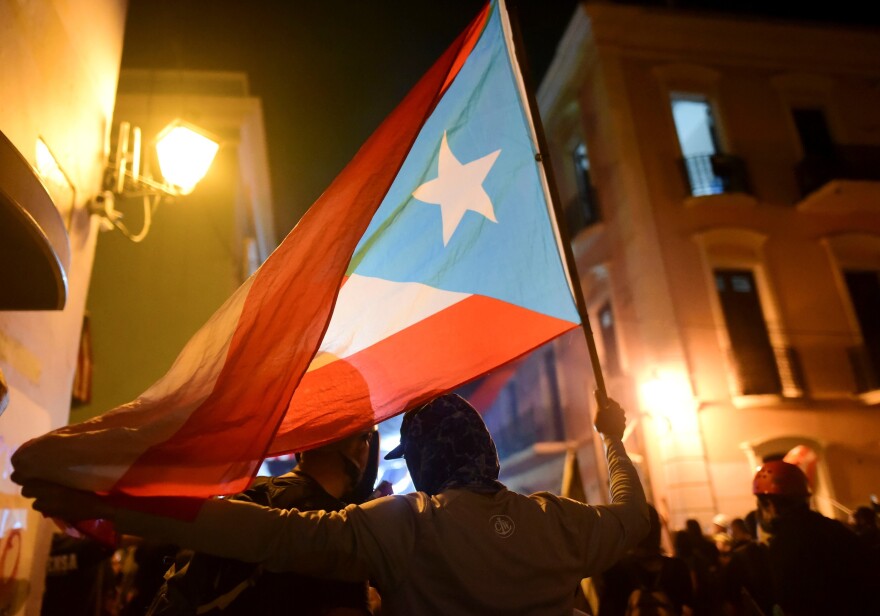 Someone holds a Puerto Rican flag.