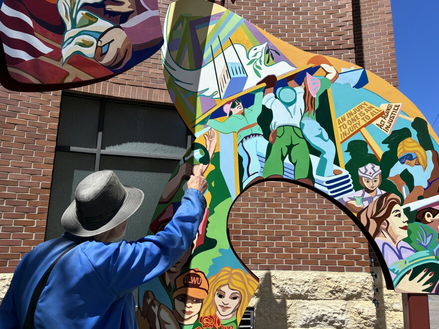 Historian Bob Cherny points out details in the ILWU memorial mural-sculpture at Mission and Steuart Streets in San Francisco.