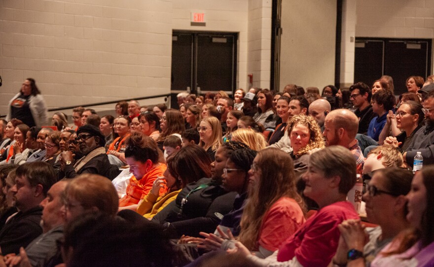 A large crowd faces forward in a packed auditorium.