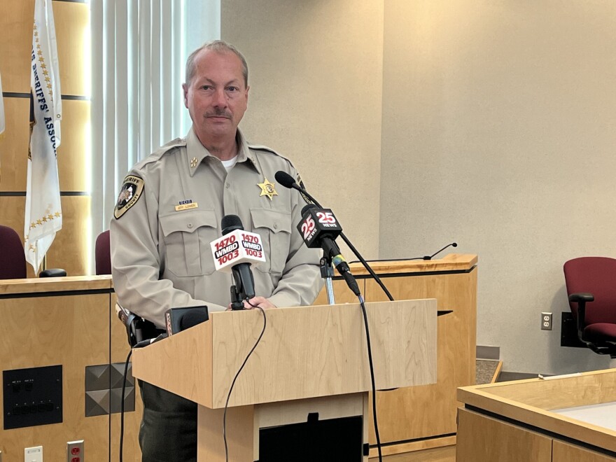 Tazewell County Sheriff Jeff Lower speaks at a press conference he stands in front of a podium with multiple microphones in a county board room.