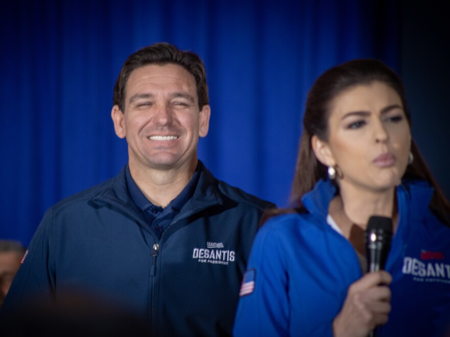 Florida Gov. Ron DeSantis looks on with a smile while his wife Casey DeSantis speaks to a crowd in Newton, Iowa following DeSantis's final county of his 99 county tour ahead of Iowa's caucuses.