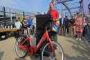 A man standing at a podium; in front of the podium is a red bike