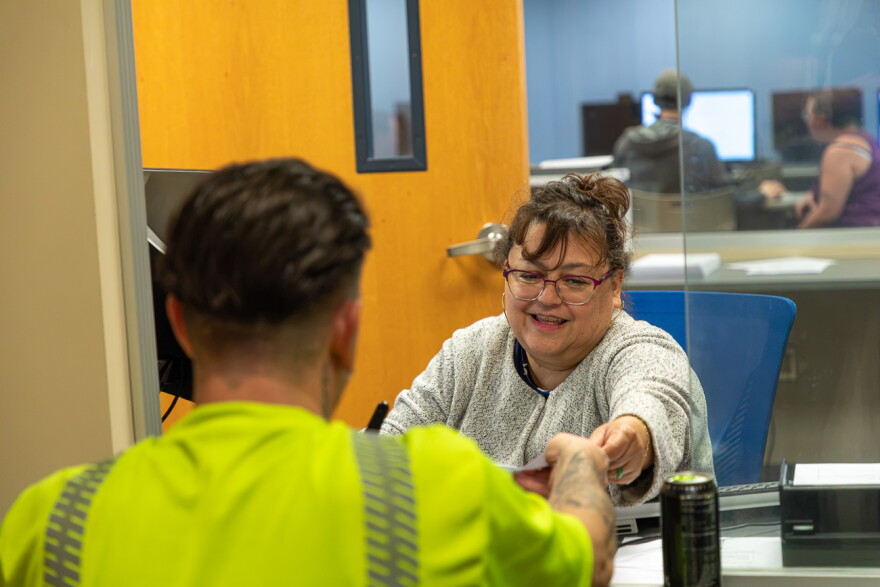 A woman working for NexStep Alliance hands enrollment forms to a prospective student on July 27.
