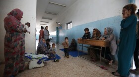 Displaced Kurdish and Arab women, who fled from violence after a Turkish offensive in northeastern Syria, sit with their children at a public school used as shelter where they now live in Hasakah, Syria.