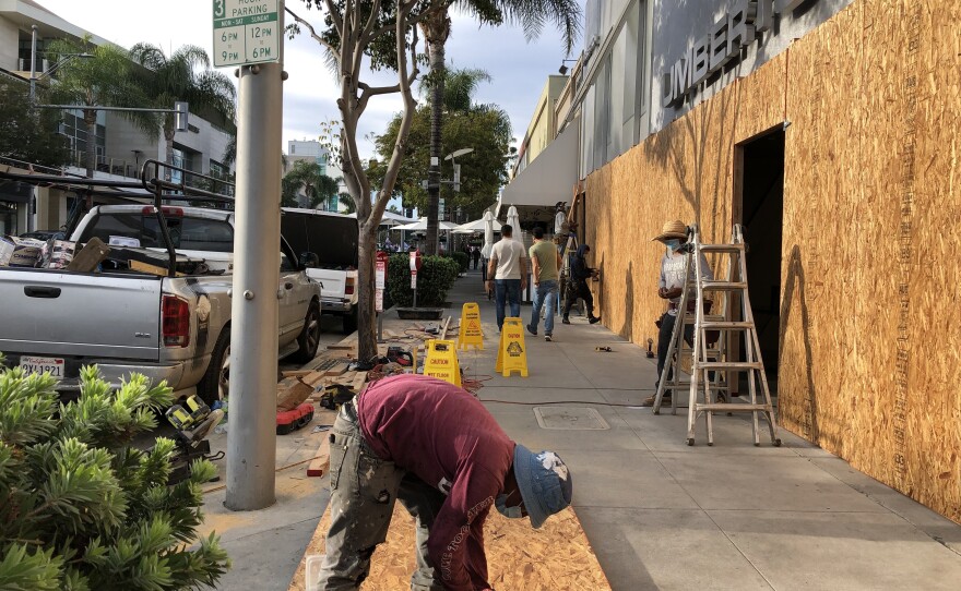 Workers board up a business in Beverly Hills, Calif., last weekend.