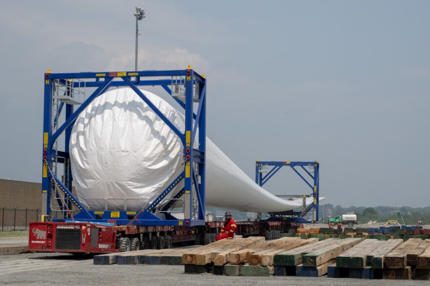 Workers help transport an offshore wind turbine blade before it is stacked on top of another at Vineyard Wind in June 2023.