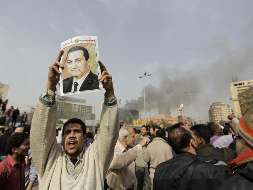 An Egyptian anti-government protester holds a defaced poster of Egyptian President Hosni Mubarak, with the words "Mubarak, get out" written above, during a demonstration in Cairo in January.