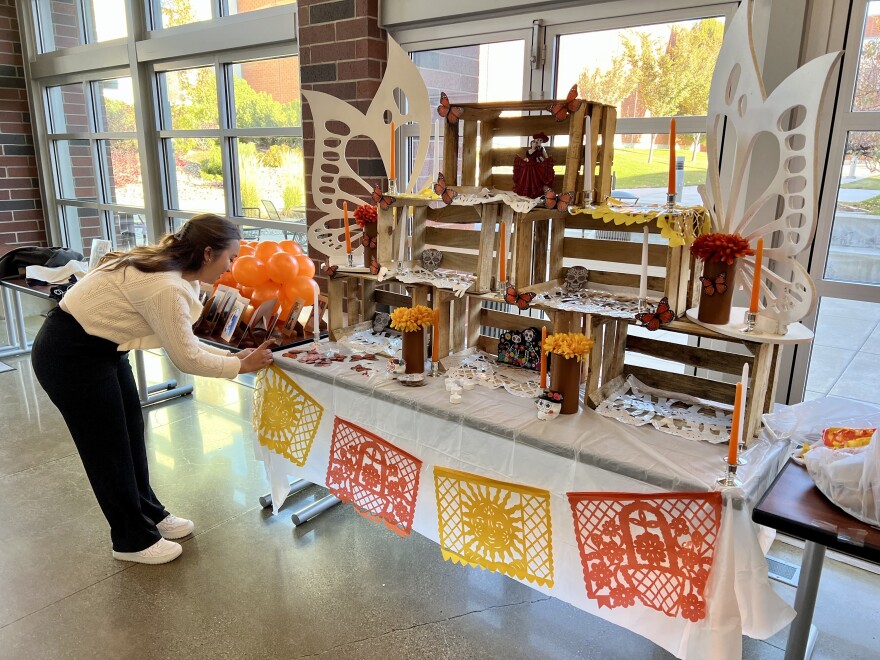 A woman dressed in a sweater and pants is placing decorative butterflies on an altar.