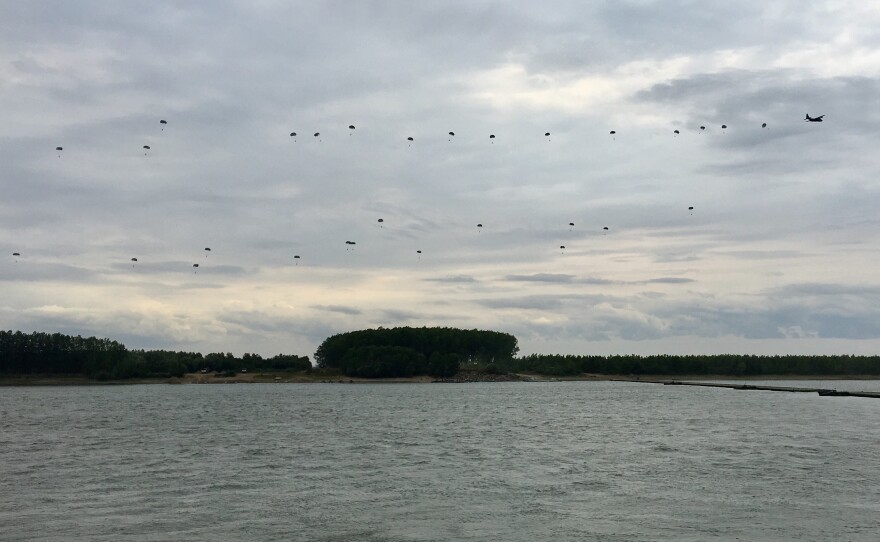 Romanian paratroopers drop from a C-130 transport to a bank of the Danube River.