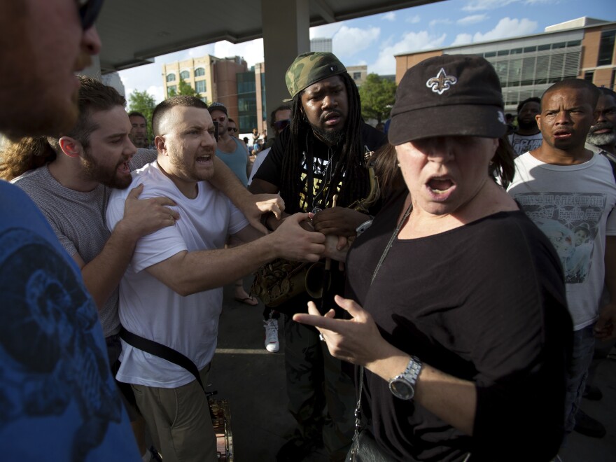 An altercation between a man in a white T-shirt, left, and a woman, right, breaks out as statue Lee is removed.