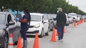 Employees of Nomi Health check in a long line of people seeking COVID-19 tests Tuesday in North Miami, Fla. The omicron variant has unleashed a fresh round of fear and uncertainty for travelers, shoppers and partygoers across the U.S.