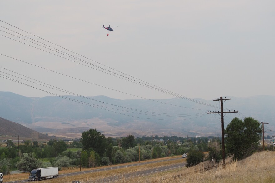 A helicopter bound for the Rocky Canyon Fire carries water over the Henefer Valley and Interstate 84 at noon Aug. 10, 2026.
