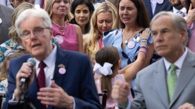 Families impacted by the Fourth of July floods stand behind Lt. Governor Dan Patrick and Governor Greg Abbott in tears during a signing ceremony of House Bill 1, which requires camps to approve plans with the state, train staff on flood emergencies, and install emergency warning systems, and Senate Bill 1, which prohibits camp cabins within outlined floodplains and requires cabins to display evacuation routes.