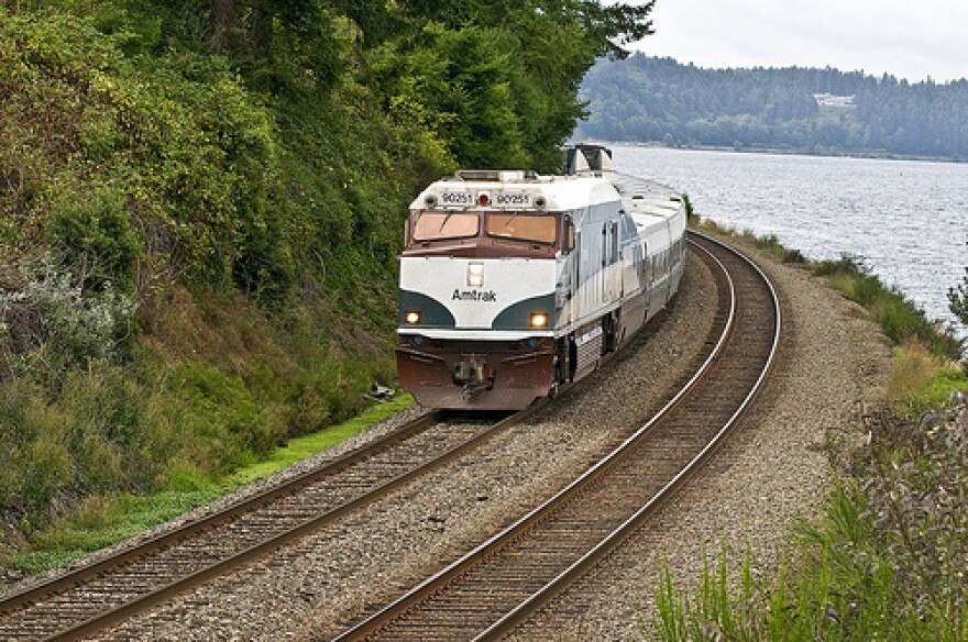 The Amtrak Cascades passenger train running along the bottom of a steep bluff near Steilacoom