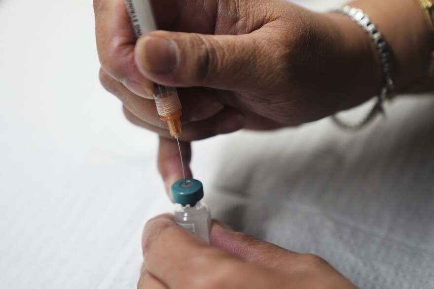 A person prepares a vaccine dose 
