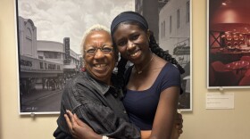 A young girl and an older woman stand embracing each other. 