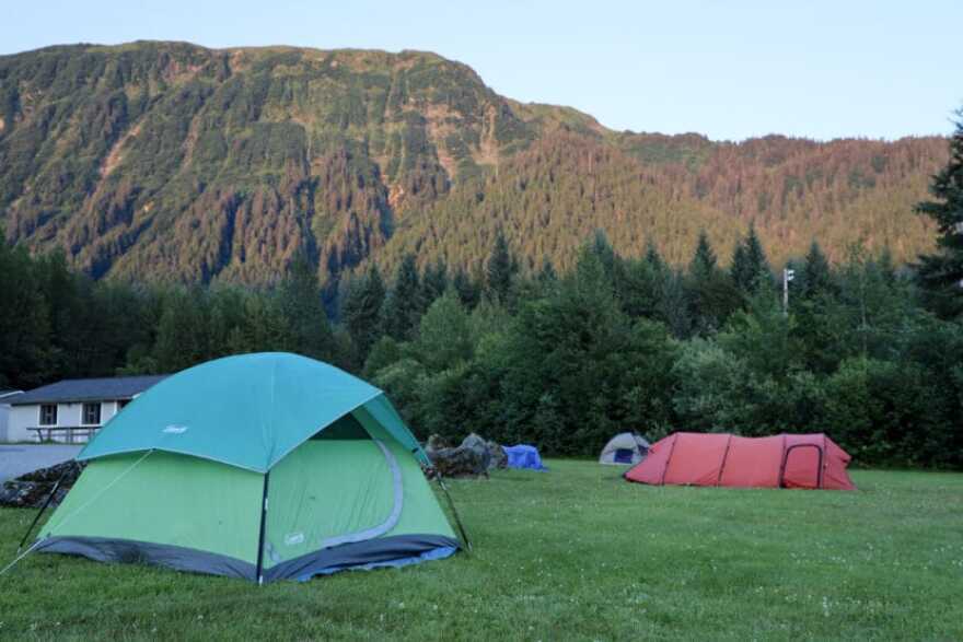 People camp on grass outside of the former Floyd Dryden Middle School building the night before the 2024 glacial outburst flood on Monday, Aug. 5, 2024.