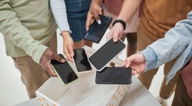 Top view closeup of diverse group of teenagers putting smartphones in box in no gadget classroom at school, copy space