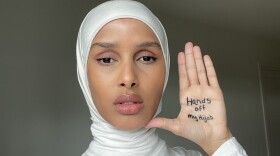 Rawdah Mohamed, wearing a hijab, holding up her hand, which says "Hands off my hijab." (Rawdah Mohamed) 