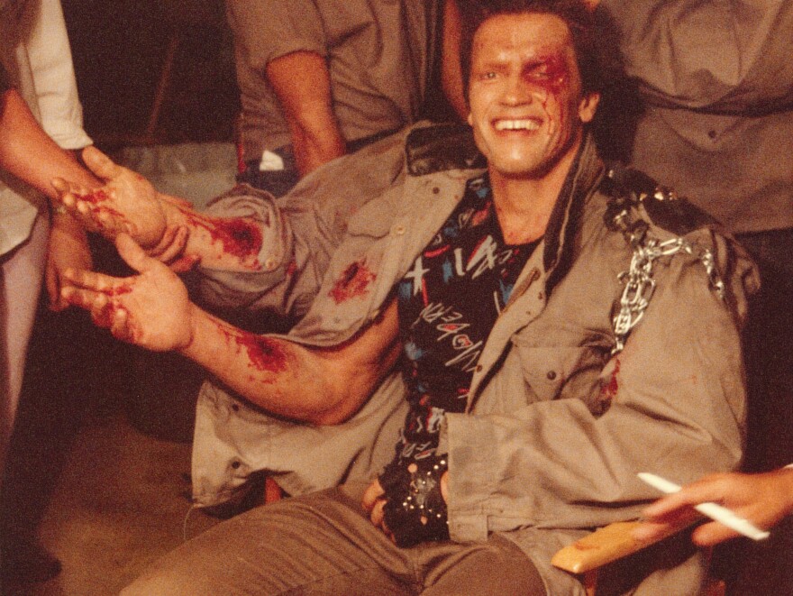 Arnold Schwarzenegger in the makeup trailer for <em>Terminator</em>, getting his do-it-yourself forearm.