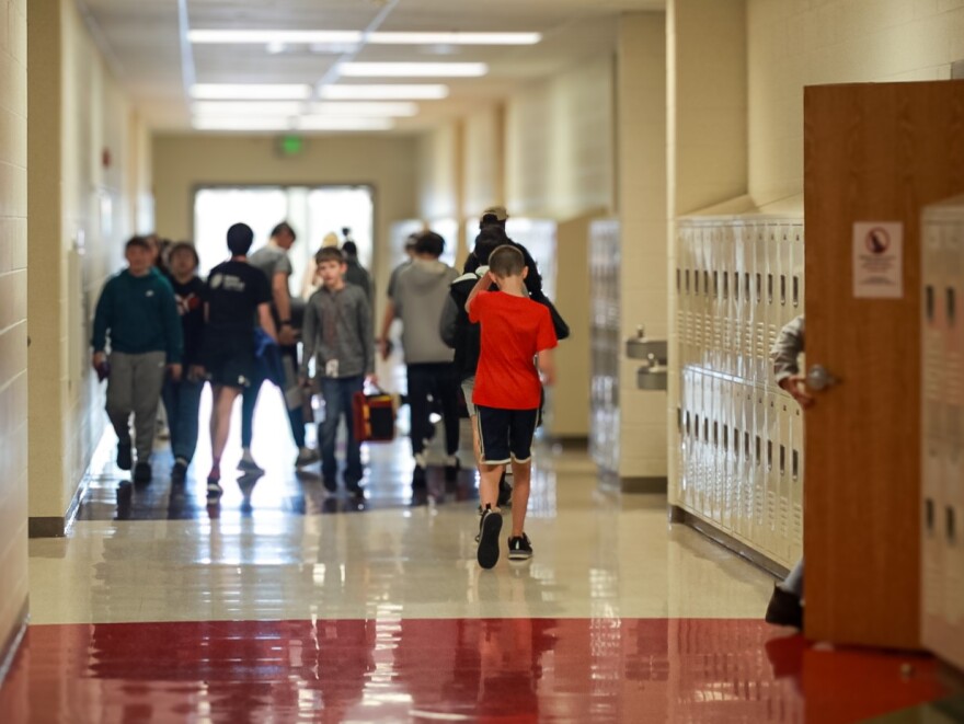 Students walk in a school hallway.