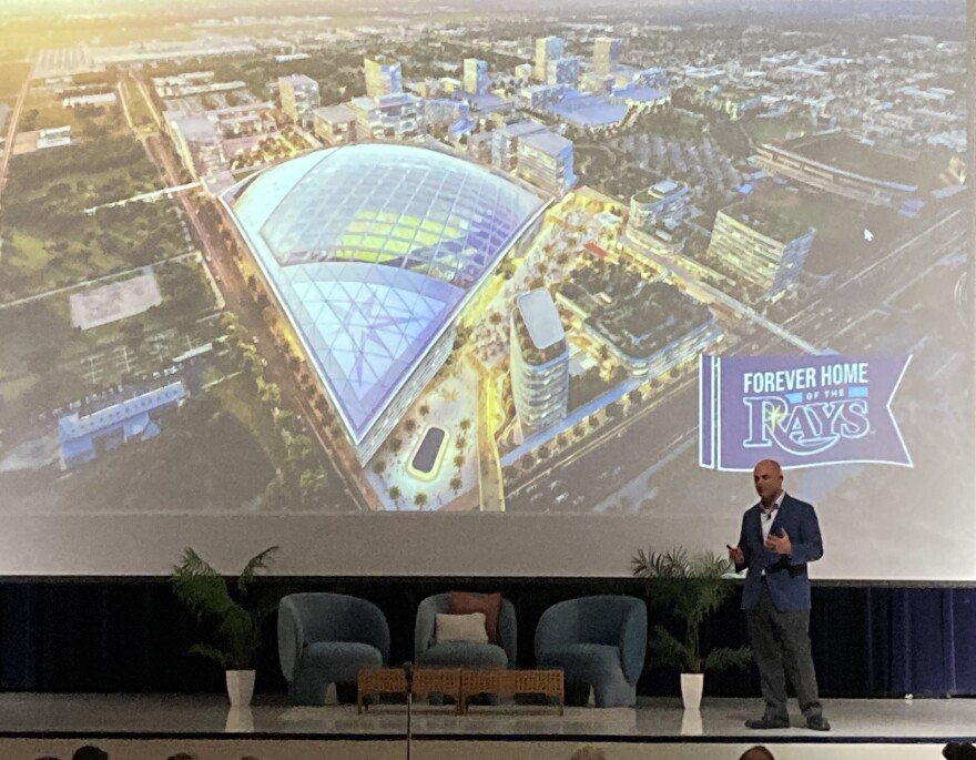 Man on stage in front of a large screen