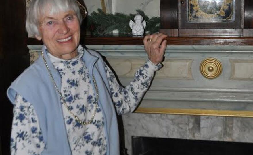 Woman standing by mantle and looking into camera.