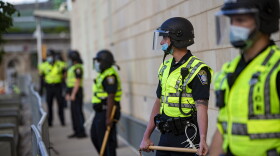 Boston police officers with batons lined up outside the District B-2 station in Roxbury before a protest on May 31. (Jesse Costa/WBUR)
