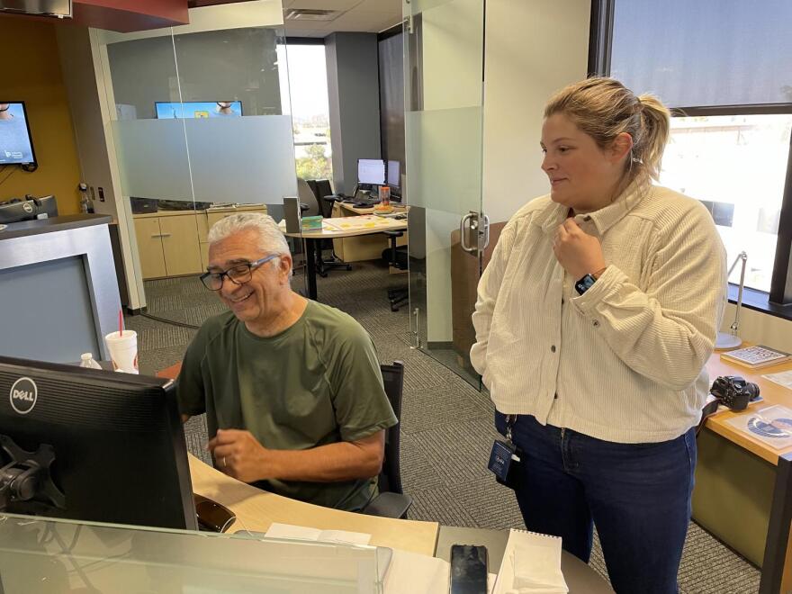Man at desk with woman standing next to him