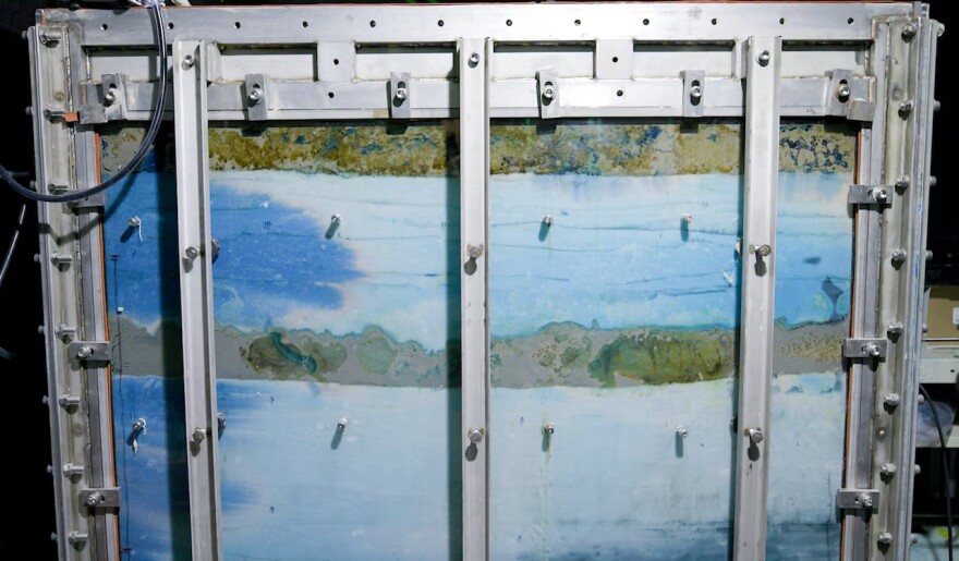 A metal-ribbed tank filled with blue and green liquids