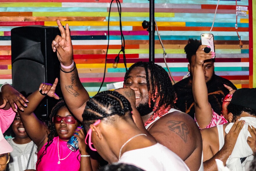 Des Moines rapper GnarlyJevy performs in the middle of a large, sweaty crowd in a rainbow-colored room