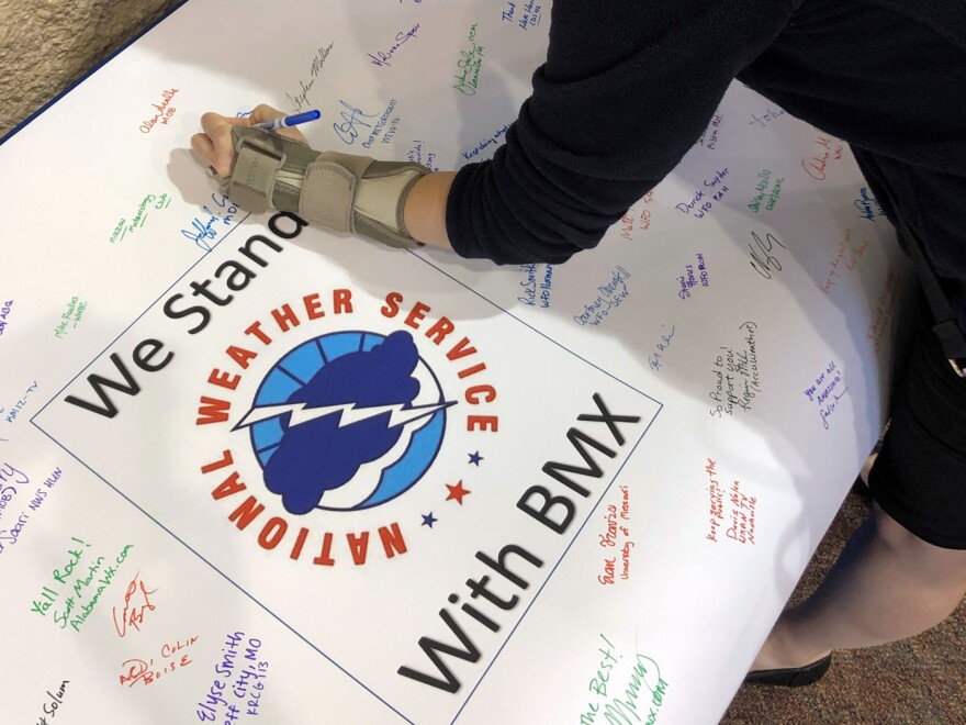 Christina Crowe signs a poster in support of the National Weather Service office in Birmingham, Ala., during a convention of the National Weather Association.