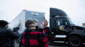 Susan Deur of Plainwell, center, and Nancy Galloway of Plainwell, left, applaud and cheer as they watch the trucks carrying Covid-19 vaccine leave from Pfizer Global Supply in Portage, Mich., Sunday, Dec. 13, 2020.