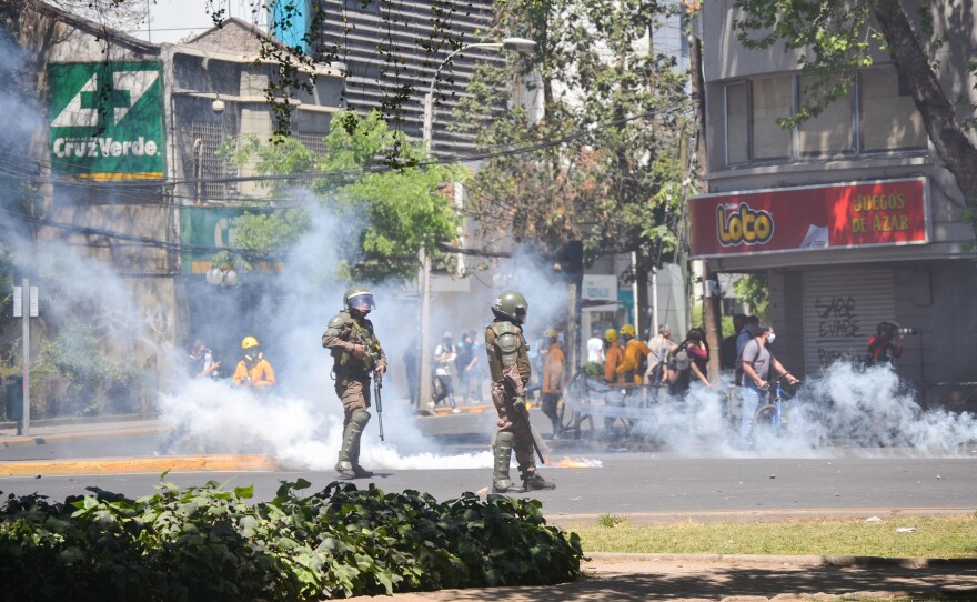 Riot police shoot tear gas and water cannons into a crowd of protesters in downtown Santiago on Monday.