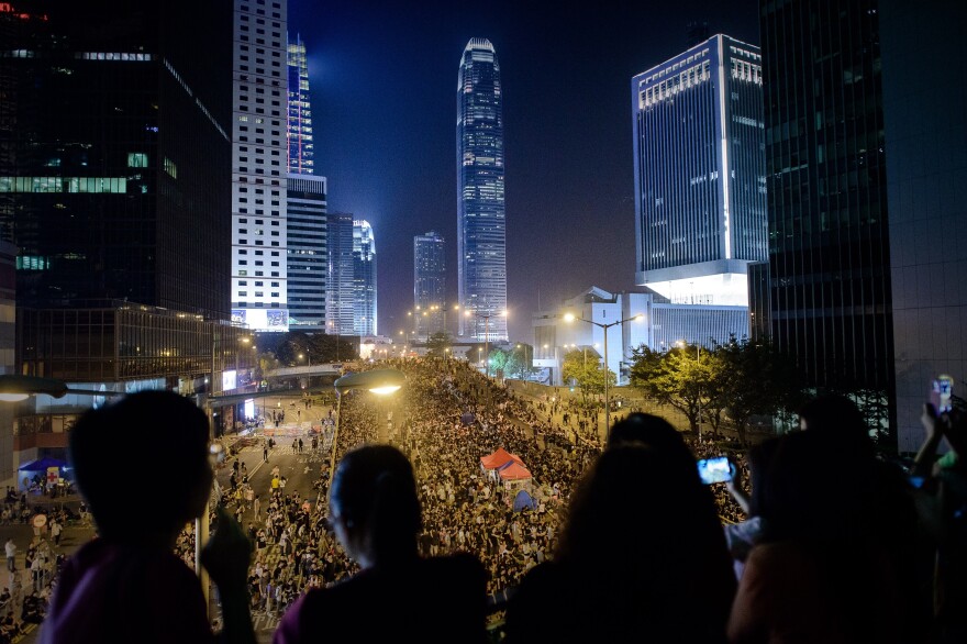 People watch as pro-democracy demonstrators gather for a Saturday night rally in Hong Kong. Hong Kong has been plunged into its most serious political crisis since its 1997 handover.