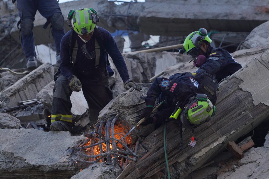 Rescue workers cut through debris as they search for survivors the day after an earthquake struck Cali, Colombia, Tuesday, Aug. 11, 2026. (AP Photo/Ivan Valencia)