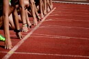 We see hands perched on a starting line as athletes prepare for a running competition