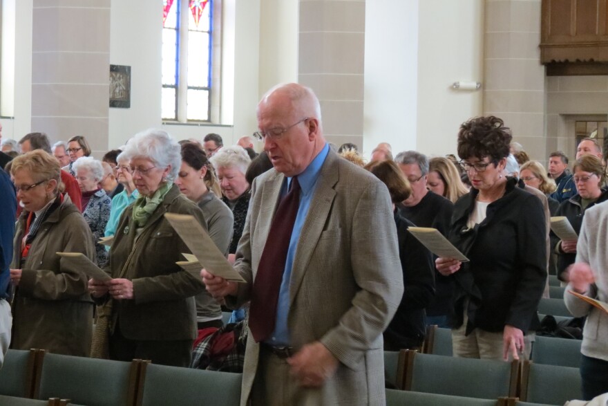 Kalamazoo residents and friends of the victims singing a hymn during the noontime mass on Monday.