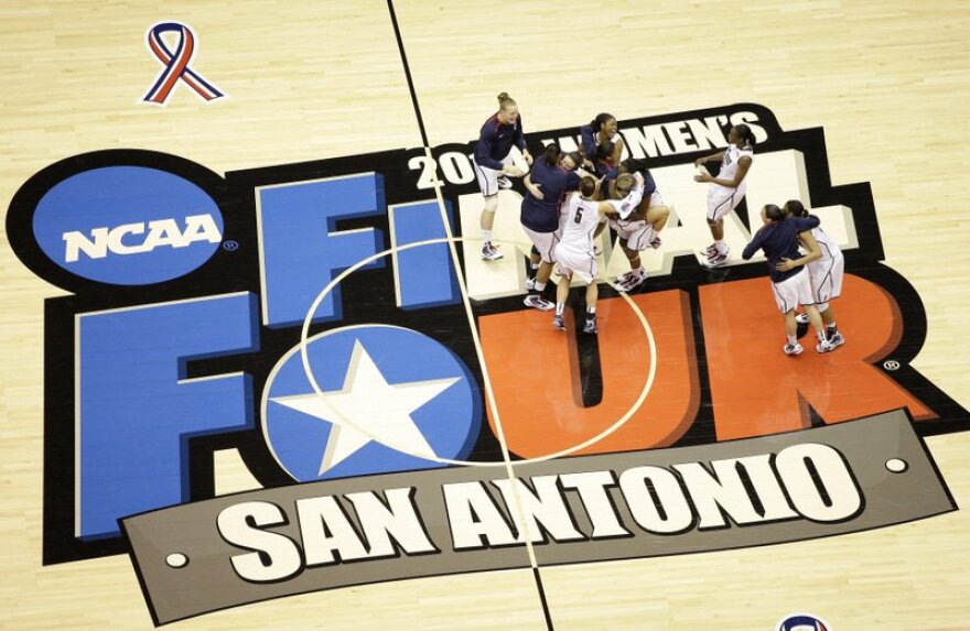 Women's basketball players celebrate at midcourt after winning a championship. The floor reads "Final Four San Antonio".