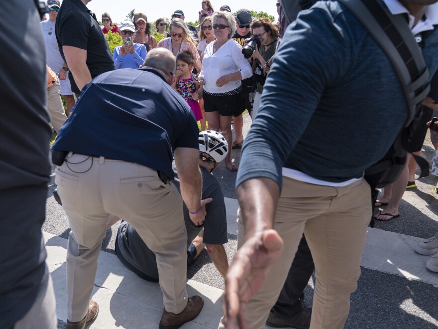 President Biden is helped by U.S. Secret Service agents after he fell trying to get off his bike to greet a crowd on a trail at Gordons Pond in Rehoboth Beach, Del., on Saturday.