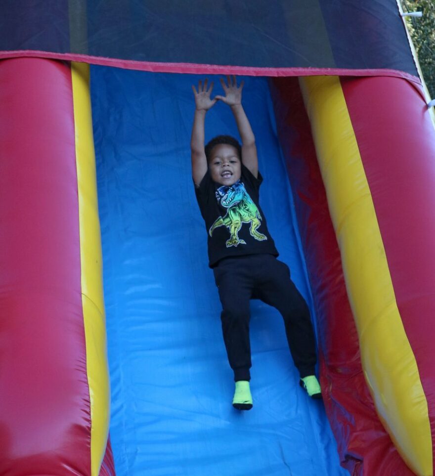 Caleb William slides down an inflatable slide. Afterwards, he waits his turn before jumping into the inflatable bounce. (Shelly Westervelt/WUFT NEWS)