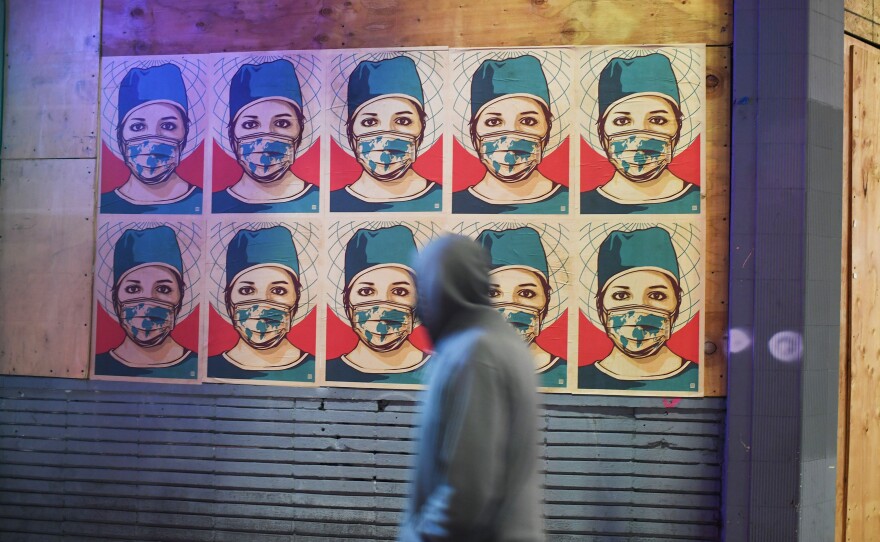 A pedestrian walks past posters showing a health care worker wearing a mask in Los Angeles. California became the second state to surpass 1 million coronavirus infections last week.
