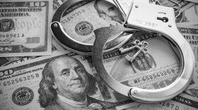 Pair of metal police handcuffs on US dollar banknotes 