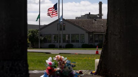The Washington state flag, American flag and Nippon Dynawave flags fly at half-staff while flowers mark a makeshift memorial on old mill equipment in front of Nippon Dynawave Packaging Co. for the victims of the May 26 chemical disaster, in Longview, Wash., on May 29, 2026.