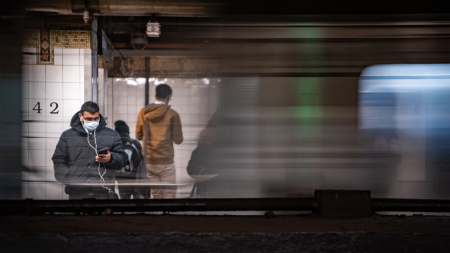 A commuter wearing a medical mask waits for a train Thursday at Grand Central Station in New York City. Several dozen cases have been confirmed in New York state, and the East Coast as a whole saw its first two confirmed deaths related to COVID-19, in Florida.