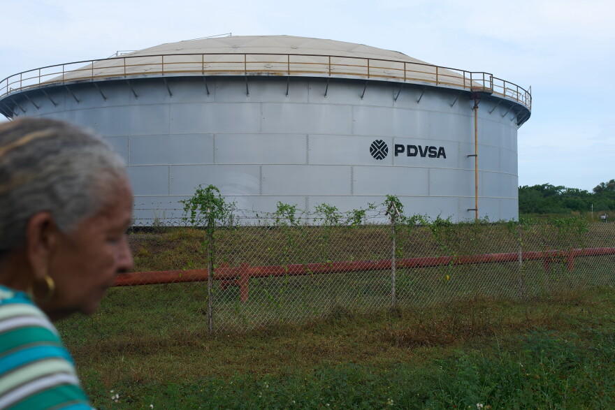 A woman walks near of a oil storage tank of Venezuela's state-run oil company, PDVSA